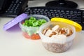 Lunch on work place. Food box container with fresh salad, buckwheat and chicken on the working desk with keyboard. Royalty Free Stock Photo