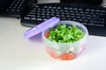 Lunch on work place. Food box container with fresh salad on the working desk with keyboard. Royalty Free Stock Photo