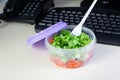 Lunch on work place. Food box container with fresh salad on the working desk with keyboard. Royalty Free Stock Photo