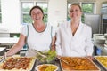 Lunchladies beside trays of food in a school Royalty Free Stock Photo