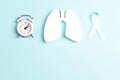 Lung cancer awareness background with white ribbon, alarm clock and lungs on blue. Copy space for text Royalty Free Stock Photo