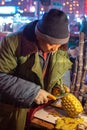 Man cutting and selling pineapple on street food fruit stall in Luoyang, China