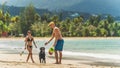 A young attractive couple play with their dog on a beach