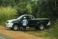 A police car and a black police officer stand on a rural road