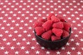 Luscious fresh picked raspberries in a black ceramic bowl on a background of white stars on a field of red Royalty Free Stock Photo