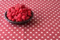 Luscious fresh picked raspberries in a large black ceramic bowl on a background of white stars on a field of red Royalty Free Stock Photo