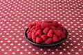 Luscious fresh picked raspberries in a large black ceramic bowl on a background of white stars on a field of red Royalty Free Stock Photo