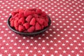 Luscious fresh picked raspberries in a large black ceramic bowl on a background of white stars on a field of red Royalty Free Stock Photo