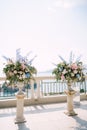 Lush bouquets of flowers in stone vases stand on the observation deck overlooking the sea