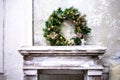 Lush Christmas wreath on the fireplace. Old white fireplace against a glassy wall