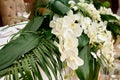 Lush floral arrangement of orchids and monstera leaves on wedding table. Wedding presidium in restaurant, copy space. Royalty Free Stock Photo