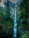 Lush forest surrounds a tranquil river, where a waterfall cascades over a bridge Royalty Free Stock Photo