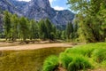 Green grass and trees on the right with the clear clean Merced River in the middle with Sentinel Rock in the background in Royalty Free Stock Photo