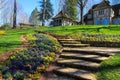 A lush green hillside with a staircase, lush green grass, colorful flowers, bare winter trees with blue sky at Gibbs Gardens Royalty Free Stock Photo