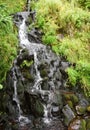 Lush green landscape surrounding a small waterfall Royalty Free Stock Photo