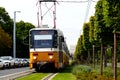 Lush green lawn along the streetcar rail tracks. Yellow tram in closeup perspective. urban street in summer Royalty Free Stock Photo