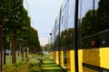 Lush green lawn along the streetcar rail tracks. Yellow tram in closeup perspective. urban street in summer Royalty Free Stock Photo