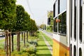 Lush green lawn between the streetcar rail tracks. Yellow tram in closeup perspective. urban street in summer Royalty Free Stock Photo