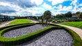 Lush green modern garden with statues under blue cloudy sky