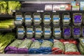 Lush green romaine lettuce and spring mix in clam shells with green and red grape tomatoes, celery and peppers on a shelf