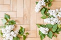 Lushly blooming white lilac branches with green leaves on a wooden geometric background