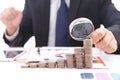 Lustful businessman with a magnifying glass in hand carefully observes a row of dollar coins Royalty Free Stock Photo