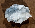 Lustrous Apophyllite crystal cluster from India on wet sand near water on the beach at sunrise