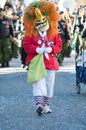 Masked person with orange wig parading in the street