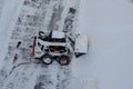 Lutsk, Ukraine - December 2, 2020. Bobcat skid steer loader removes snow from the city streets. Top view of the road with cars and Royalty Free Stock Photo