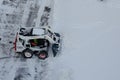 Lutsk, Ukraine - December 2, 2020. Bobcat skid steer loader removes snow from the city streets. Top view of the road with cars and Royalty Free Stock Photo