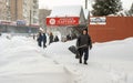 Lutsk, Ukraine - February 12,2020: An elderly man with snow shovel in winter. City street after blizzard. People walk in