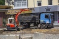 Lutsk, Ukraine - July 08, 2021: Excavation work during the renovation of the street. Excavator and truck are working. A mini