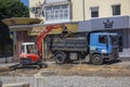 Lutsk, Ukraine - July 08, 2021: Excavator and truck are working. Excavation work during the renovation of the street. A mini