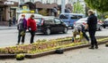 Lutsk, Ukraine - May 11,2020: Flower gardeners at work wear protective mask on a public street during coronavirus epidemic.