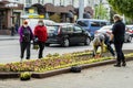 Lutsk, Ukraine - May 11,2020: Flower gardeners at work wear protective mask on a public street during coronavirus epidemic.