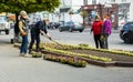 Lutsk, Ukraine - May 11,2020: Flower gardeners at work wear protective mask on a public street during coronavirus epidemic.