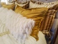 Luxiourous gold and fur pillow shams on bed propped against quilted beadstead