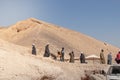 LUXOR, EGYPT - 27 Dec 2022. Group of local arab muslims working in the desert digging the sand in mountain under blue