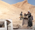 LUXOR, EGYPT - 27 Dec 2022. Old arab egyptian man with turban working in the mountain with working trolley and sand