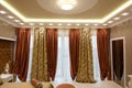 Luxurious bard curtains on the window of the mansion. Exit to the balcony. Square-shaped ceiling lighting