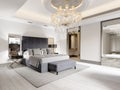 Luxurious bedroom with white walls and a gray fabric bed with black bedside tables and lamps and a large luminous crystal