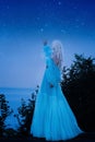 A luxurious blue dress with a long train flutters in the wind. Photo from the back without a face. Woman reaches for the stars Royalty Free Stock Photo