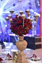 A luxurious bouquet of fresh flowers in a golden vase on the table with cutlery plates and an elegant portion in the party