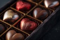 A luxurious box of assorted chocolate hearts wrapped in metallic red and gold foil, offering an indulgent treat for