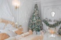 Luxurious Classic Bright White Bedroom Interior with Christmas New Year Tree decor and lights Royalty Free Stock Photo