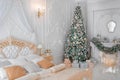 Luxurious Classic White Bedroom Interior with Christmas New Year Tree decor and lights Royalty Free Stock Photo