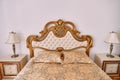 Luxurious double bed with soft carved wooden headboard and bedside tables