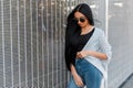 Luxurious elegant pretty young hipster woman in trendy jeans in a black t-shirt in a summer cape in sunglasses with long hair Royalty Free Stock Photo
