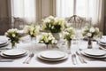 Luxurious elegant table setting with white dishes and flowers. Dining table for a celebration or wedding reception Royalty Free Stock Photo