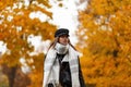 Luxurious European young woman in warm stylish autumn outerwear in an elegant black hat with a trendy scarf walks through the Royalty Free Stock Photo